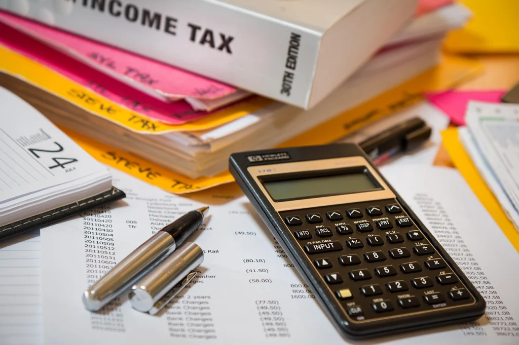 Calculator and notebook on a desk used to plan monthly payments for a 0% APR purchase card or store financing plan