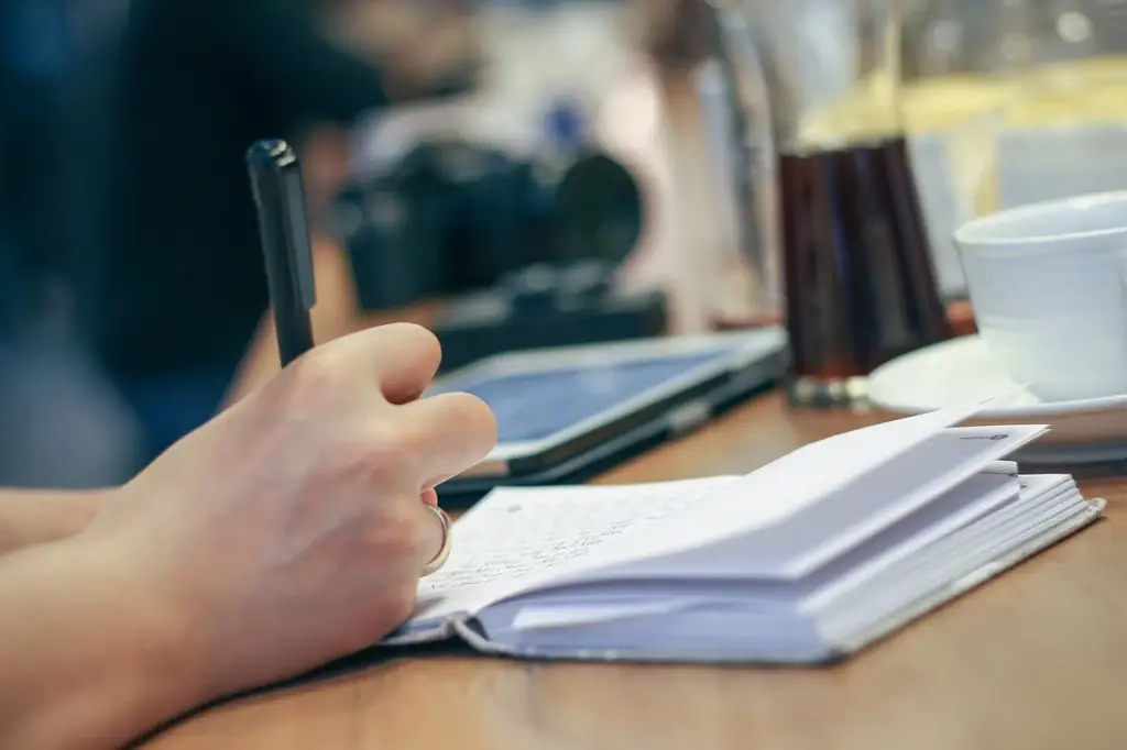 Person writing down credit card promo end dates in a planner to track 0% APR periods